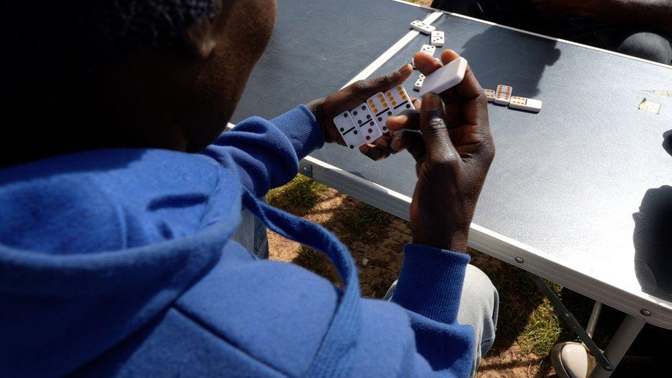 Migrants in the Calais camp play dominos