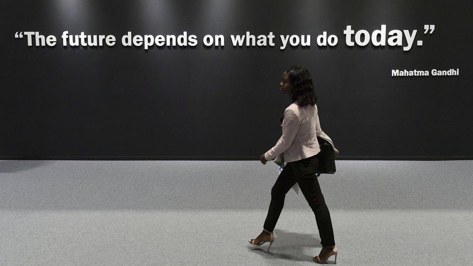 A participant walks past a wall showing a quote by Indian pacifist Mahatma Gandhi at the UN Climate Change Conference