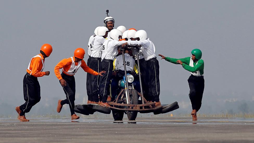 Members of ASC "Tornadoes", the motorcycle display team of Indian army, run to climb onto a motorcycle as they attempt to create a world record for most men on a single moving motorcycle at Yelahanka Air Force Station in Bengaluru