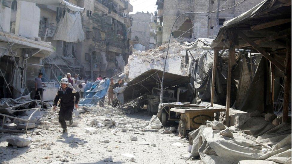 A civil defence member runs in market hit by air strikes in al-Fardous district of Aleppo