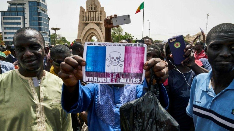 A Malian protester holds a sign depicting the French flag and reading "Death to France and its allies", Bamako, 5 April