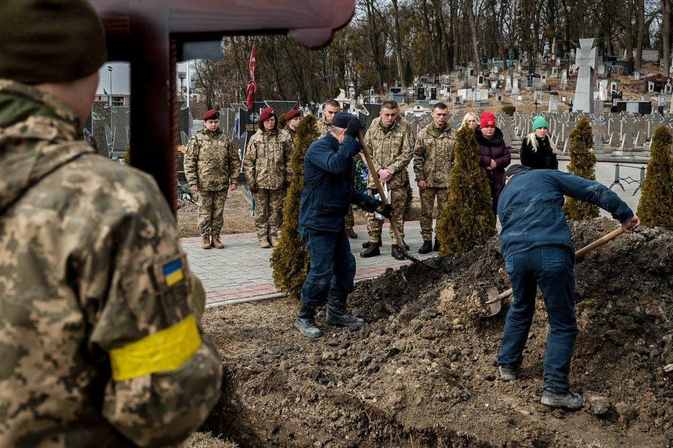 The gravediggers at the Lychakiv Cemetery cover Kotenko's coffin with earth