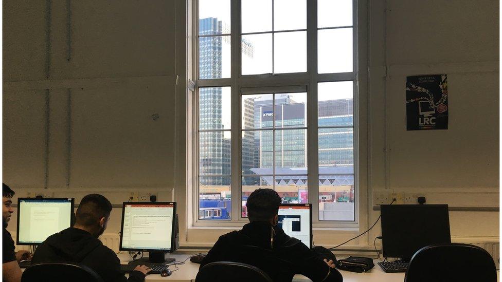 Pupils looking over of the window of Tower Hamlets College, where classrooms overlook Canary Wharf