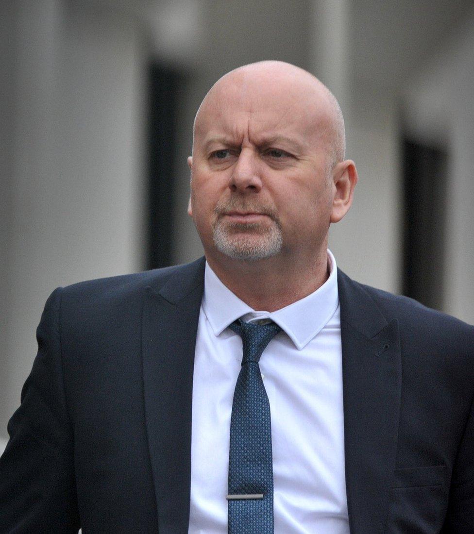 Craig Scott outside Swansea Crown Court. He has a balding / shaven head and a grey stubbly goatee. He is wearing a navy suit and tie and a white t shirt.