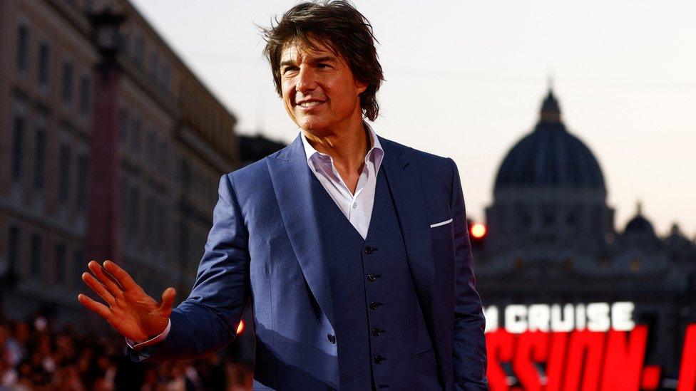 Actor Tom Cruise waving at a crowd during the world premiere of his film