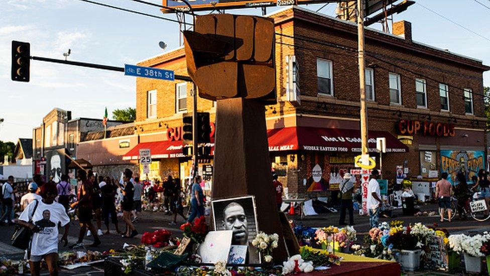 A sculpture of a raised fist stands in a memorial for George Floyd outside Cup Foods