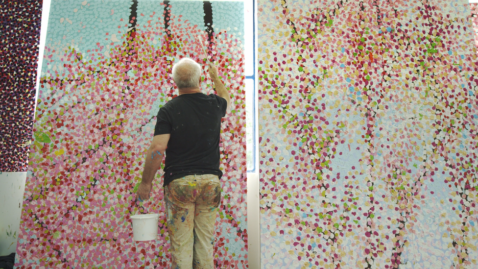 Damien Hirst stands in front of his canvases - © Damien Hirst and Science Ltd. All rights reserved, DACS 2021