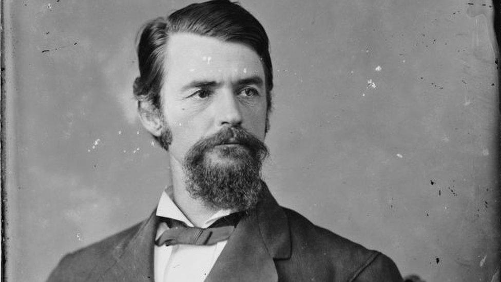 Black and white photo of man with goatee and moustache, wearing bow tie.