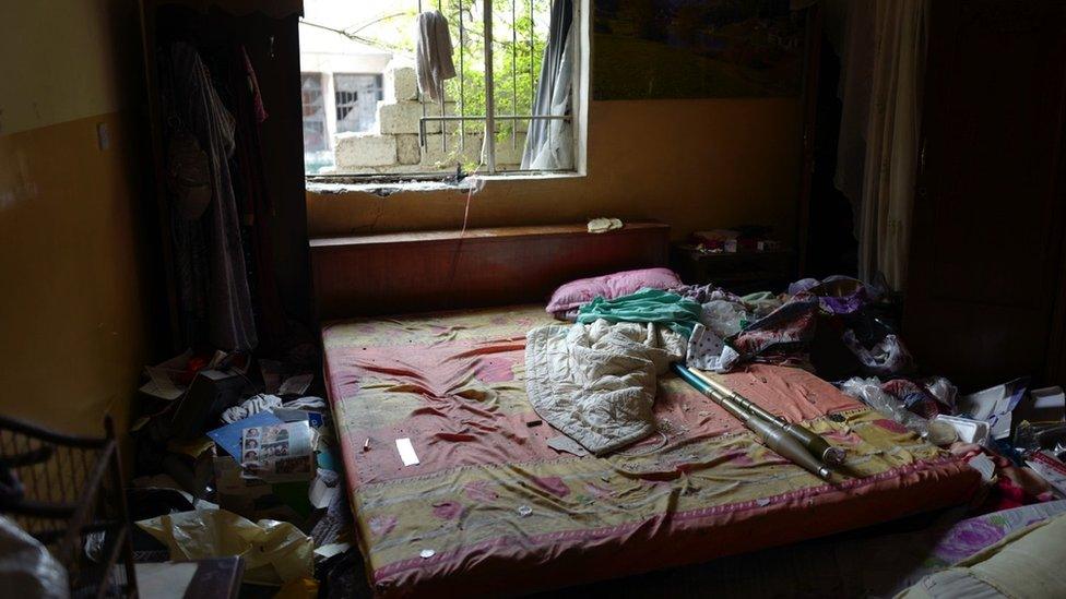 A messy bedroom with rockets thrown across the bed before the window. Originally tweeted by @BowenBBC with the caption: "Another bedroom on the front line in #Mosul, more privacy invaded. Clothes still in the wardrobe. RPGs on the bed."