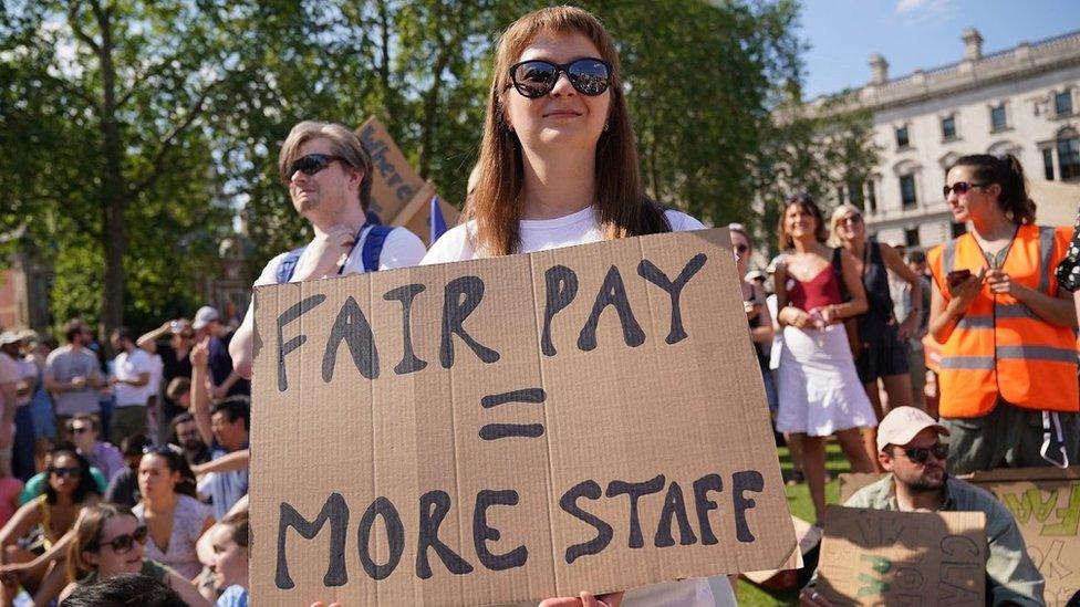 A woman holds a sign saying "fair pay equals more staff" during a junior doctors' strike