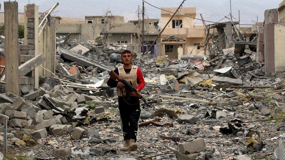 A volunteer from the Yazidi sect who joined the Kurdish peshmerga forces walks with his weapon in the town of Sinjar, Iraq, on 16 November 2015