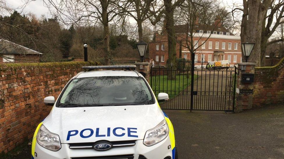 Police car parked outside the house's gates