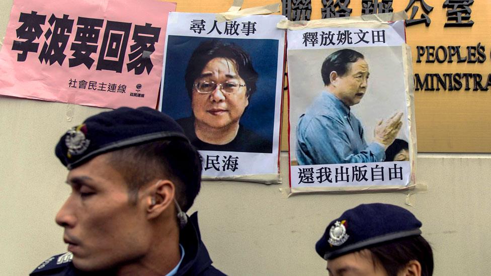 This file picture taken on January 3, 2016 shows police walking past missing person notices of Gui Minhai