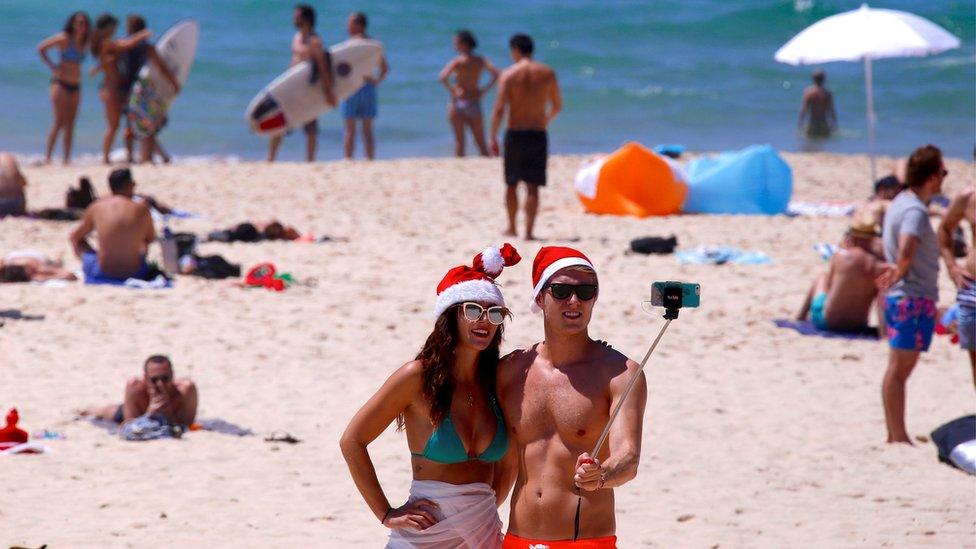 Tourists take a selfie as they wear Christmas hats and celebrate Christmas Day at Sydney's Bondi Beach in Australia, 25 December, 2016.