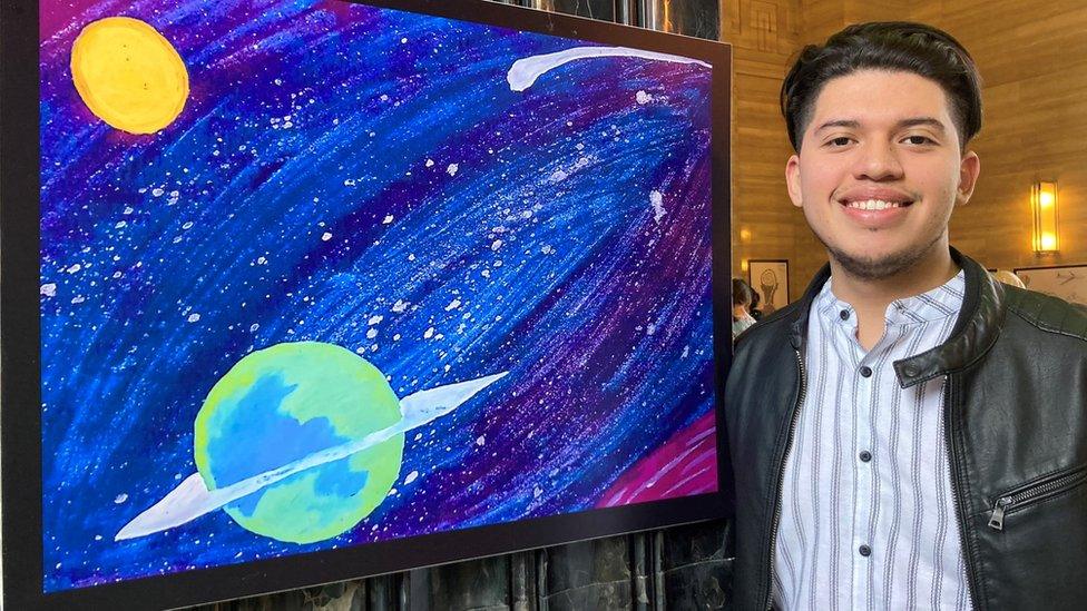 Eduardo smiling next to his artwork