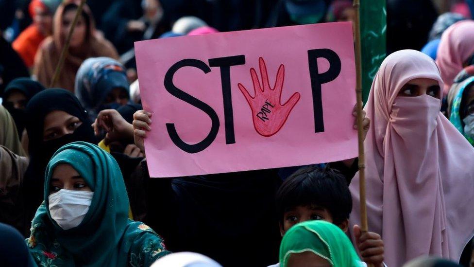 A woman holds a placard reading "Stop" during a protest against an alleged gang rape of a woman in Pakistan, 2020