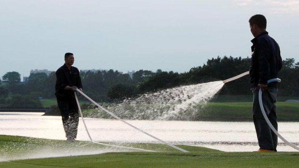 People watering a golf course