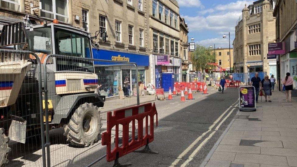 The town centre of Yeovil with shoppers walking down the street surrounded by cones and fences and roadworks and construction machinery