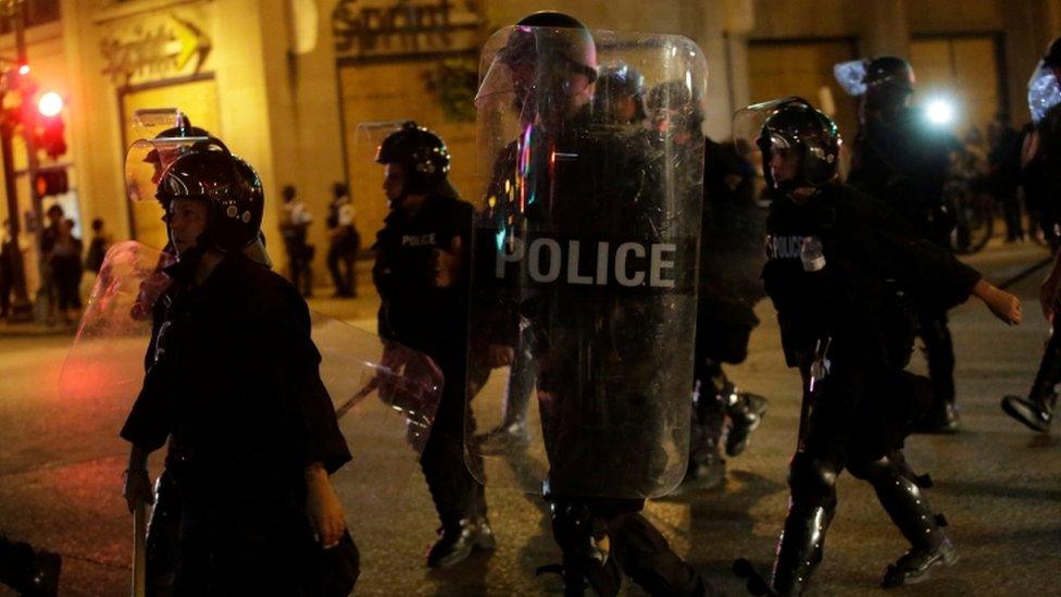 Police officers with riot gear march in St Louis street