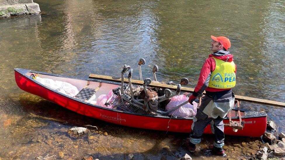 Man with a canoe containing rubbish