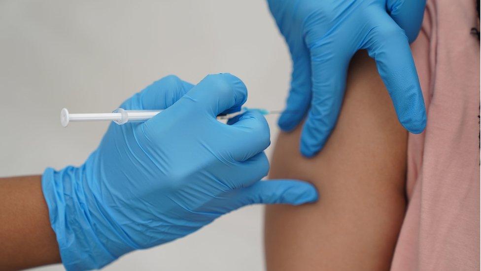 Health worker gives vaccine