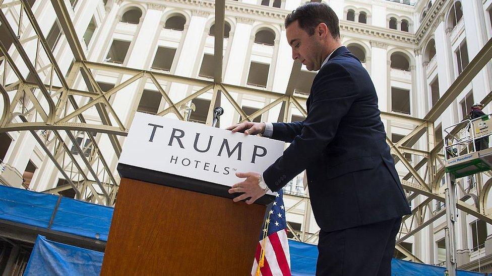 A staffer attaches a placard to a podium prior to Republican presidential candidate Donald Trump's press conference at the still under construction Trump International Hotel in Washington, DC, March 21, 2016.