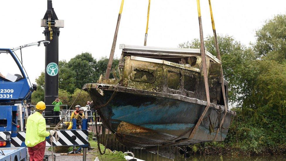 Sunken boat being lifted up from the river