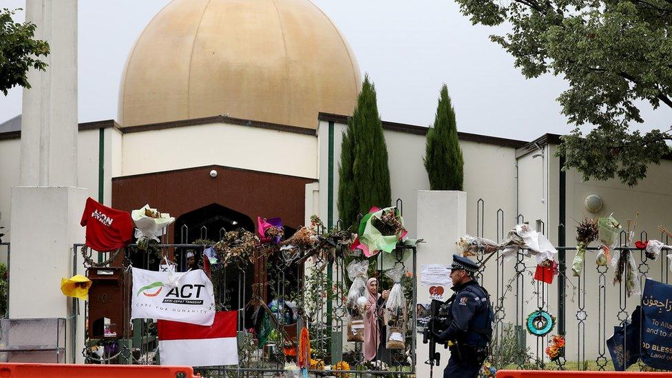 An armed police officer stands guard outside the Al Noor mosque in Christchurch where dozens were killed in March