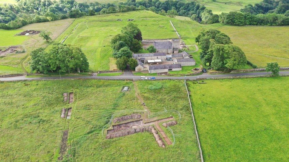 Aerial view showing multiple exposed digs in fields around the Roman fort