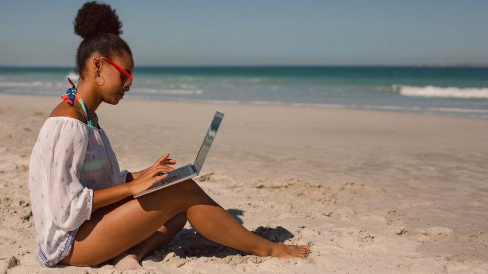 A woman on the beach with a laptop