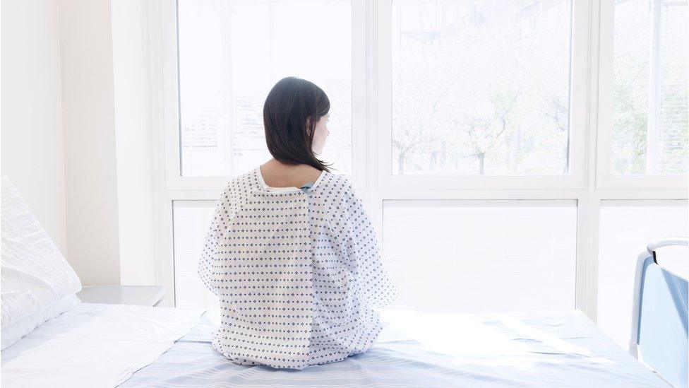 Woman in hospital gown on bed