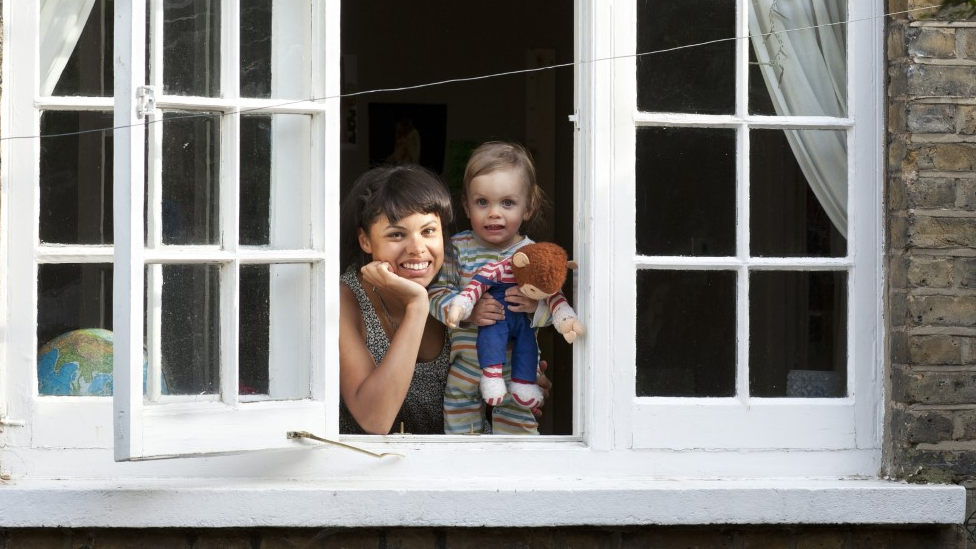 Woman and toddler looking out of an open window