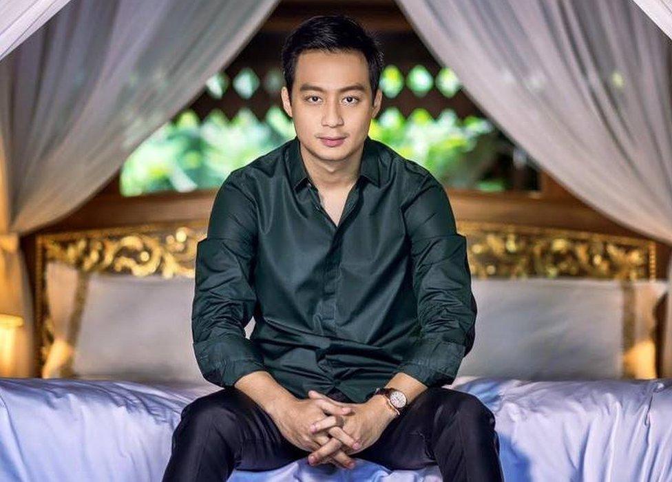 Nay Shwe Thway Aung posing for a picture on the end of a bed