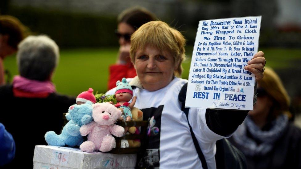 A woman holds a sign at a funeral procession in remembrance of dead children in Dublin