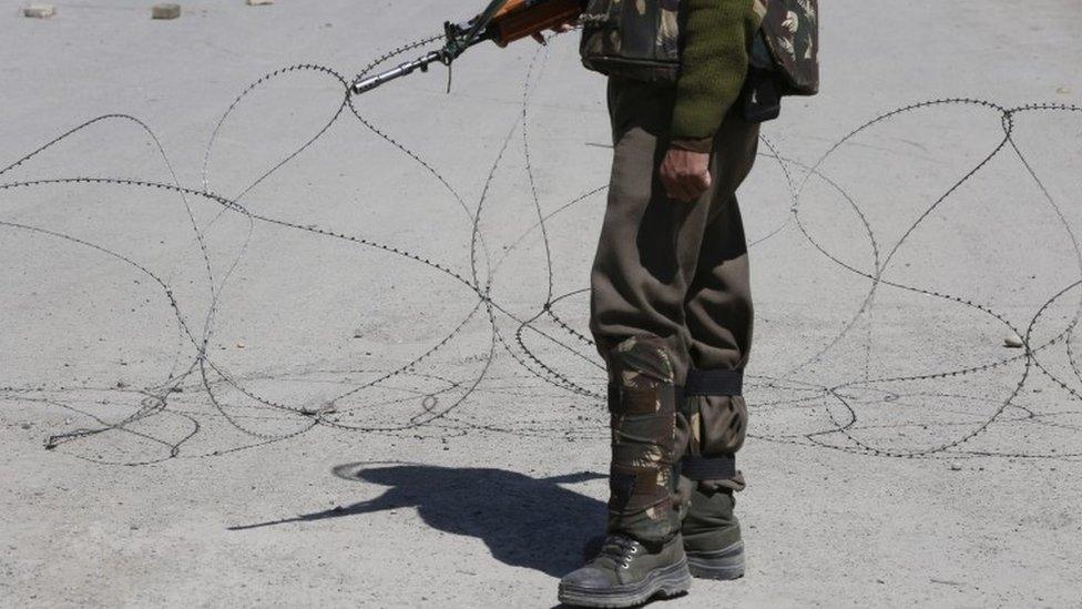 An Indian Paramilitary soldier stands guard near a barbed wire set up as a barricade during restrictions in Maisuma area of Srinagar on 14 April 2016