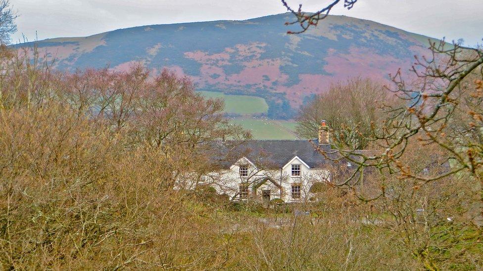 A white house in front of a red hill