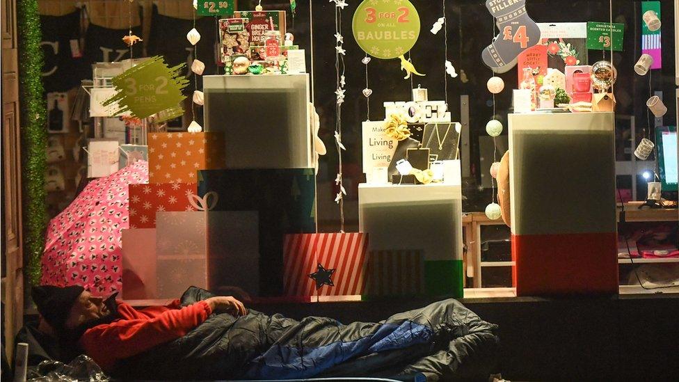 Man sleeping on the street outside a shop