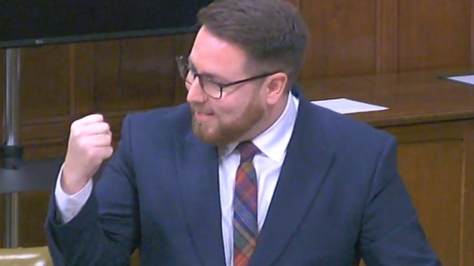 Man with beard and glasses shaking a fist and smiling