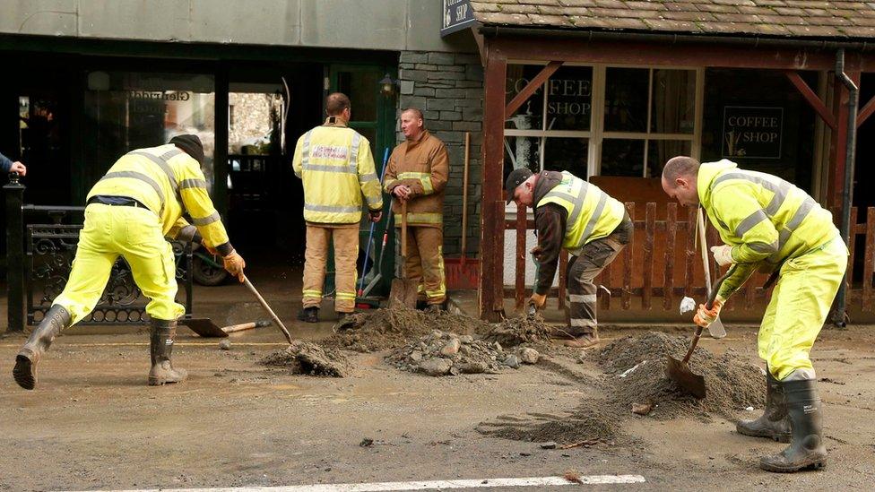 Workers clear mud and silt from the road after the river burst it's banks and flooded the village of Glenridding