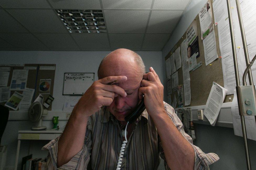 A Samaritans volunteer listens with his head in his hands.