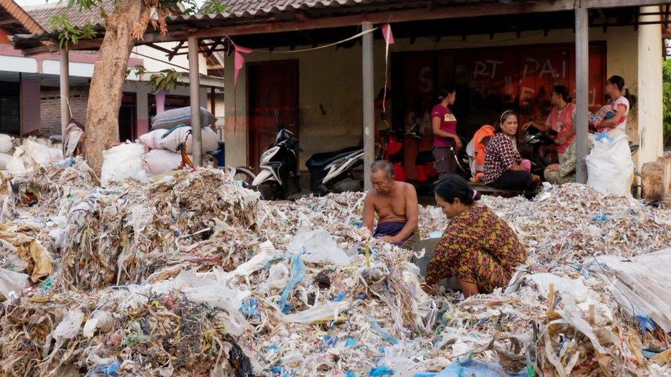 Villagers sort through plastic