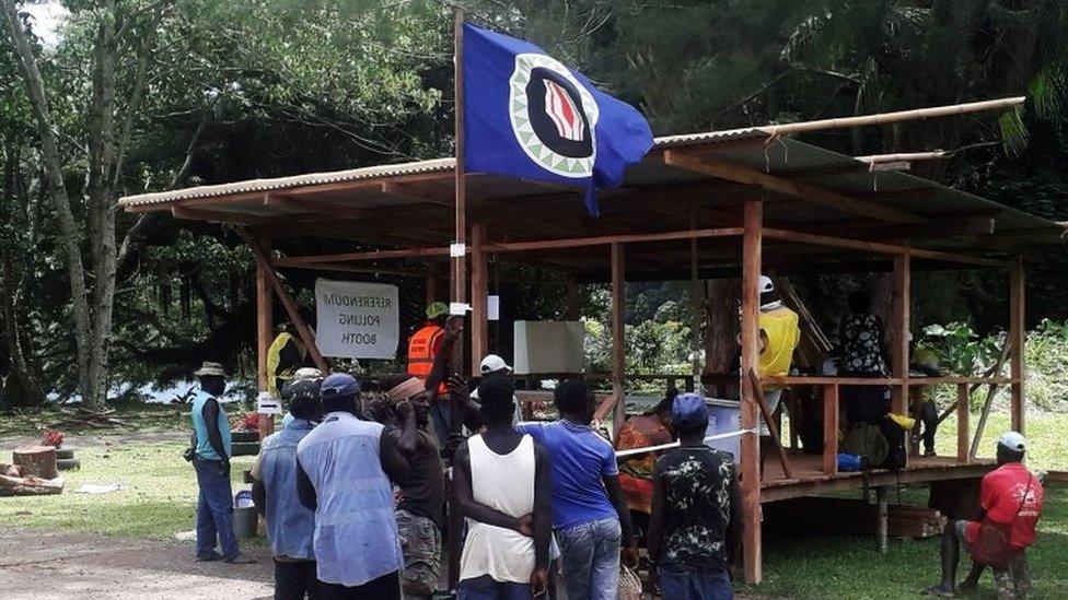 Voters hold a Bougainville flag at a polling station