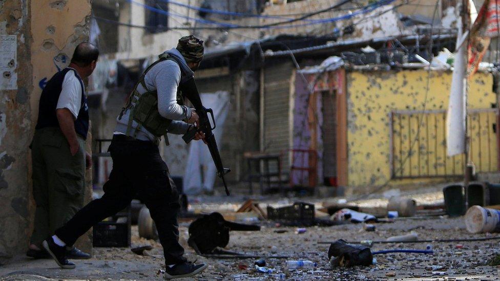 Palestinian gunmen from the Fatah faction attempt to cross a street during clashes in the Ein el-Hilweh refugee camp in Lebanon on 10 April 2017