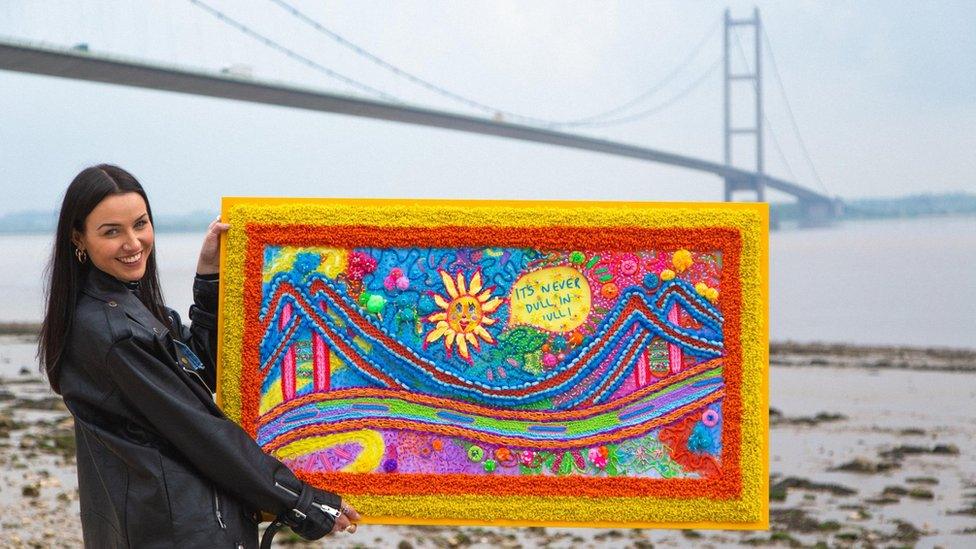 Erin Ledsom holding her embroidery artwork of the Humber Bridge