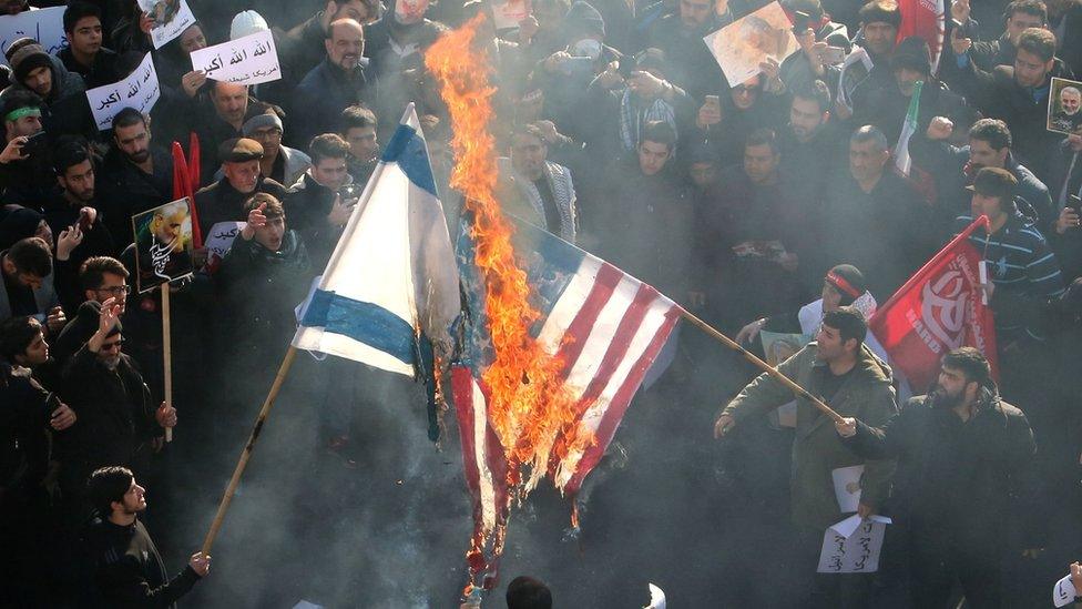 Iranians set a US and an Israeli flag on fire during a funeral procession in Tehran, 6 January 2020