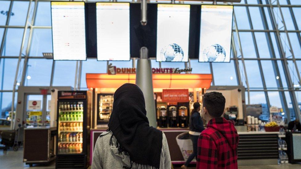 A young woman wearing a Hijab watches the arrivals board at the international terminal at John F. Kennedy International Airport, March 6, 2017 in New York City