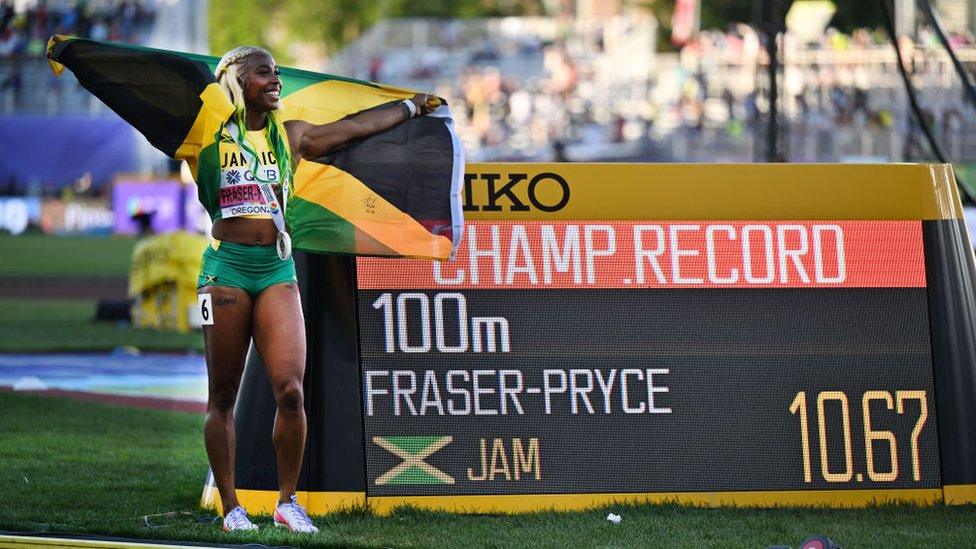 Shelly-Ann-Fraser-Pryce-standing-next-to-sign.