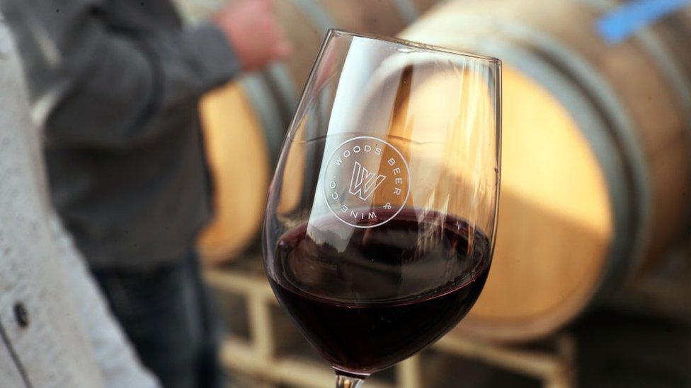 A man holding a class of Californian red wine at a bar in San Francisco