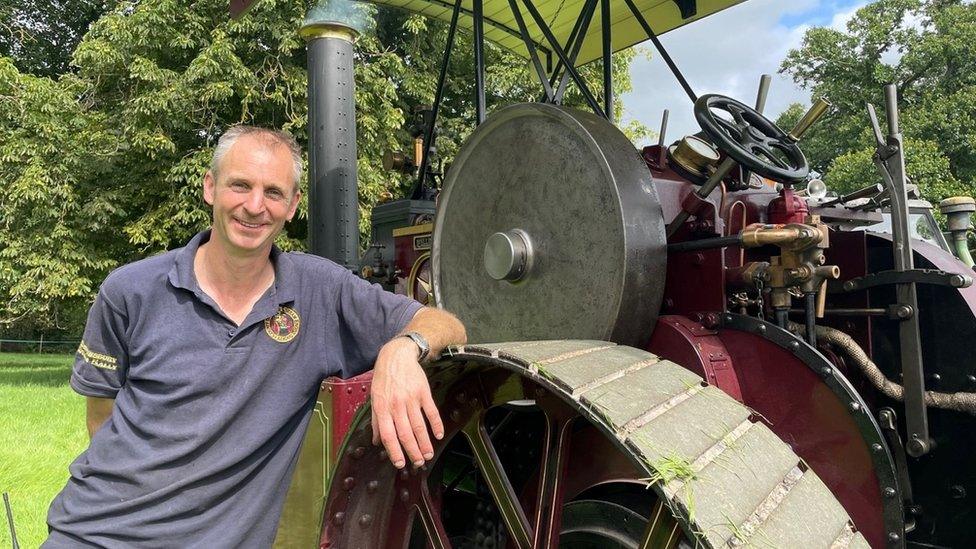 Man leaning on a wheel of a steam engine