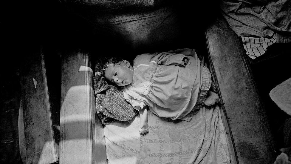 Baby asleep in an armchair in a slum property in Balsall Heath, Birmingham